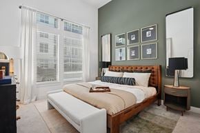 Dallas apartment for rent - A bedroom with a large bed and a window with white curtains.