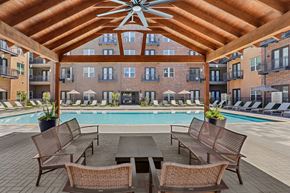 Mckinney apartment for rent - A patio with a table and chairs overlooking a pool.