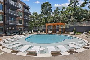 Nashville apartment for rent - A round pool surrounded by white chairs and a wooden pergola.