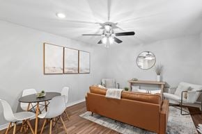 Houston apartment for rent - A living room with a brown couch, white chairs, and a ceiling fan.