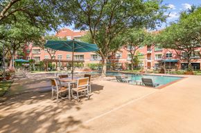 Dallas apartment for rent - A pool area with a table and chairs and a green umbrella.