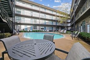 Nashville apartment for rent - a swimming pool with a table and chairs in front of an apartment building