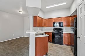 Fort Worth apartment for rent - A kitchen with brown cabinets and black appliances.