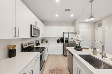 Kissimmee apartment for rent - A modern kitchen with white cabinets and stainless steel appliances.