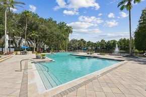 Tampa apartment for rent - A large swimming pool surrounded by trees and a fountain.
