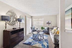 Dallas apartment for rent - A living room with a white couch, a coffee table, and a large mirror on the wall.