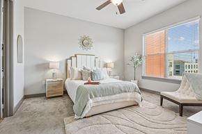 Fort Worth apartment for rent - A bedroom with a large bed, a ceiling fan, and a window with blinds.