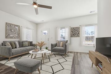 Dacula apartment for rent - A living room with a grey couch, a white coffee table, and a television on a wooden stand.