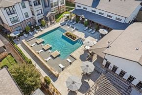 Fort Worth apartment for rent - an aerial view of an outdoor pool with chairs and umbrellas and a house