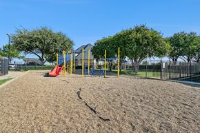 Fort Worth apartment for rent - A playground with a yellow swing set and a red slide.
