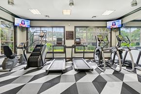 Grand Prairie apartment for rent - A gym with treadmills, exercise bikes, and a television screen.