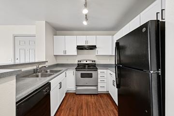 Lafayette apartment for rent - A black refrigerator stands in a kitchen with white cabinets and a stove.