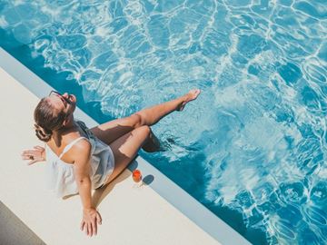 Frisco apartment for rent - A woman in a white top is sitting by a pool.