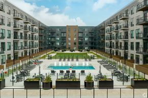 Middleton apartment for rent - A large pool surrounded by lounge chairs and planters is surrounded by apartment buildings.