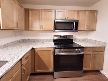 Menasha apartment for rent - A kitchen with a stove and oven in the middle of wooden cabinets.