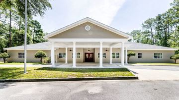 Hinesville apartment for rent - A church with a white facade and a red door is surrounded by greenery.
