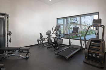 A gym with various cardio equipment on the floor and a window