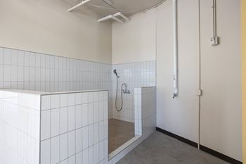 A bathroom with white tiled walls and a shower in it 