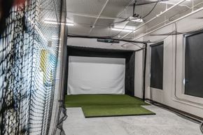 Fargo apartment for rent - a batting cage in a gym with a green carpet at Riverhouse Apartments, Fargo