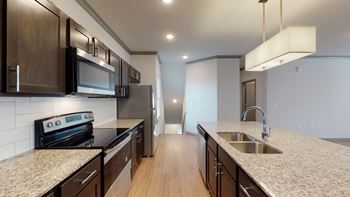 Luxury kitchen with tile backsplash, kitchen island & designer lighting