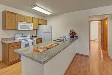 Wasilla apartment for rent - A kitchen with a granite counter top and wooden cabinets.