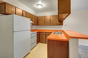 Anchorage apartment for rent - A kitchen with a white refrigerator, wooden cabinets, and a countertop.
