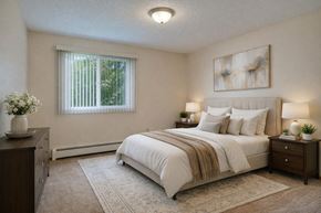 Kenai apartment for rent - A serene bedroom at Bay Arms Apartments with a cozy bed dressed in white bedding and neutral pillows. Two bedside tables with lamps frame the bed, and a dresser sits to the side with décor. A window with vertical blinds brings in natural light, brightening the carpeted space and soft area rug.
