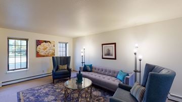 Fairbanks apartment for rent - A living room with a grey couch, a blue chair, a coffee table, and a painting on the wall.