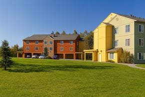 Anchorage apartment for rent - A large building with a yellow section is surrounded by a green lawn.