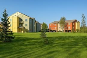 Anchorage apartment for rent - A grassy field with two buildings in the background.