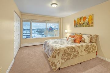 Anchorage apartment for rent - A bedroom with a large bed and a view of a snowy landscape outside the window.