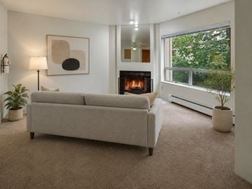 Anchorage apartment for rent - A living room with a grey couch, a fireplace, and a painting on the wall.