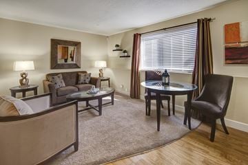 Anchorage apartment for rent - A living room with a grey couch, a black chair, a glass table, and a painting on the wall.