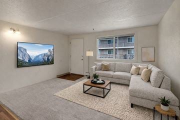 Anchorage apartment for rent - A living room with a grey couch, a coffee table, and a painting of a mountain scene on the wall.