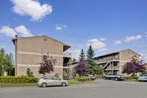 Anchorage apartment for rent - A welcoming exterior here at College View showcasing well-maintained apartment buildings with neutral siding, exterior staircases, and private balconies. Mature trees, landscaped greenery, and open parking areas create an inviting community setting, while clear walkways and open skies highlight the comfortable residential atmosphere.