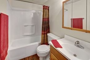 Anchorage apartment for rent - A clean, functional bathroom here at College View featuring a full tub and shower combination with built-in shelving, a bright vanity with wood cabinetry, and a mirrored medicine cabinet. Neutral walls, easy-care flooring, and coordinated fixtures create a practical, well-lit space designed for everyday comfort and convenience.