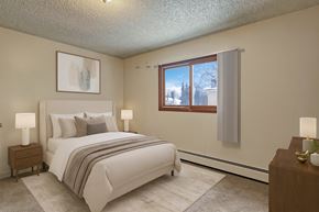 Anchorage apartment for rent - A bright bedroom here at Conifer Grove featuring neutral walls, soft carpeting, and a large window with vertical blinds that brings in natural light. The space includes a modern bed with white bedding, coordinating nightstands with lamps, and a clean, comfortable layout ideal for restful living.