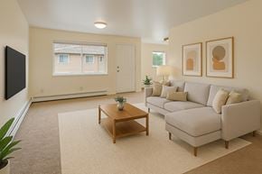 Anchorage apartment for rent - A living room with a grey couch, a wooden coffee table, and a flat screen TV mounted on the wall.