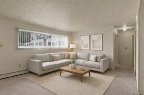 Anchorage apartment for rent - A living room with a grey couch, a coffee table, and a window with blinds.
