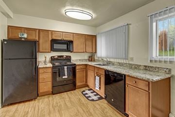 Anchorage apartment for rent - A kitchen with wooden cabinets and a black refrigerator.