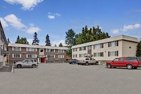 Anchorage apartment for rent - A parking lot with cars and a building in the background.
