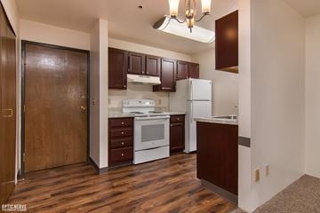 Anchorage apartment for rent - A kitchen with brown cabinets and a white fridge.