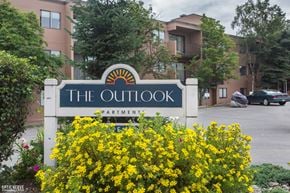 Anchorage apartment for rent - The Outlook apartments are surrounded by greenery and have a sign in front.