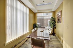Anchorage apartment for rent - A bright meeting room here at Park Plaza II with a long glass-top conference table and modern chairs, featuring large windows with vertical blinds, warm wall tones, and greenery for a professional, welcoming space.