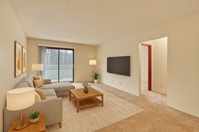 Anchorage apartment for rent - A living room with a grey couch, a wooden coffee table, a flat screen TV, and a large window.