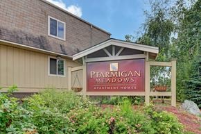 Anchorage apartment for rent - A sign for Ptarmigan Meadows Apartment Homes is displayed in front of a building.