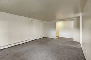 Anchorage apartment for rent - A spacious, empty living room here at Ptarmigan Meadows with soft gray carpet, clean white walls, and an open layout that offers plenty of room for flexible furniture placement.