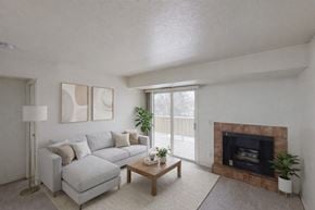 Anchorage apartment for rent - A living room with a grey couch, a fireplace, and a plant.