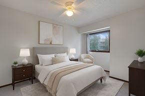Anchorage apartment for rent - A bedroom with a bed, two lamps, a painting, and a window.