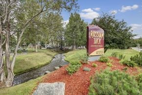 Anchorage apartment for rent - A sign for Russian Jack Apartments stands in front of a stream.